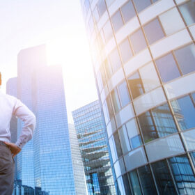 A photo of a business man looking up at corporate glass buildings. The image appears to symbolise a fresh start or new beginning.